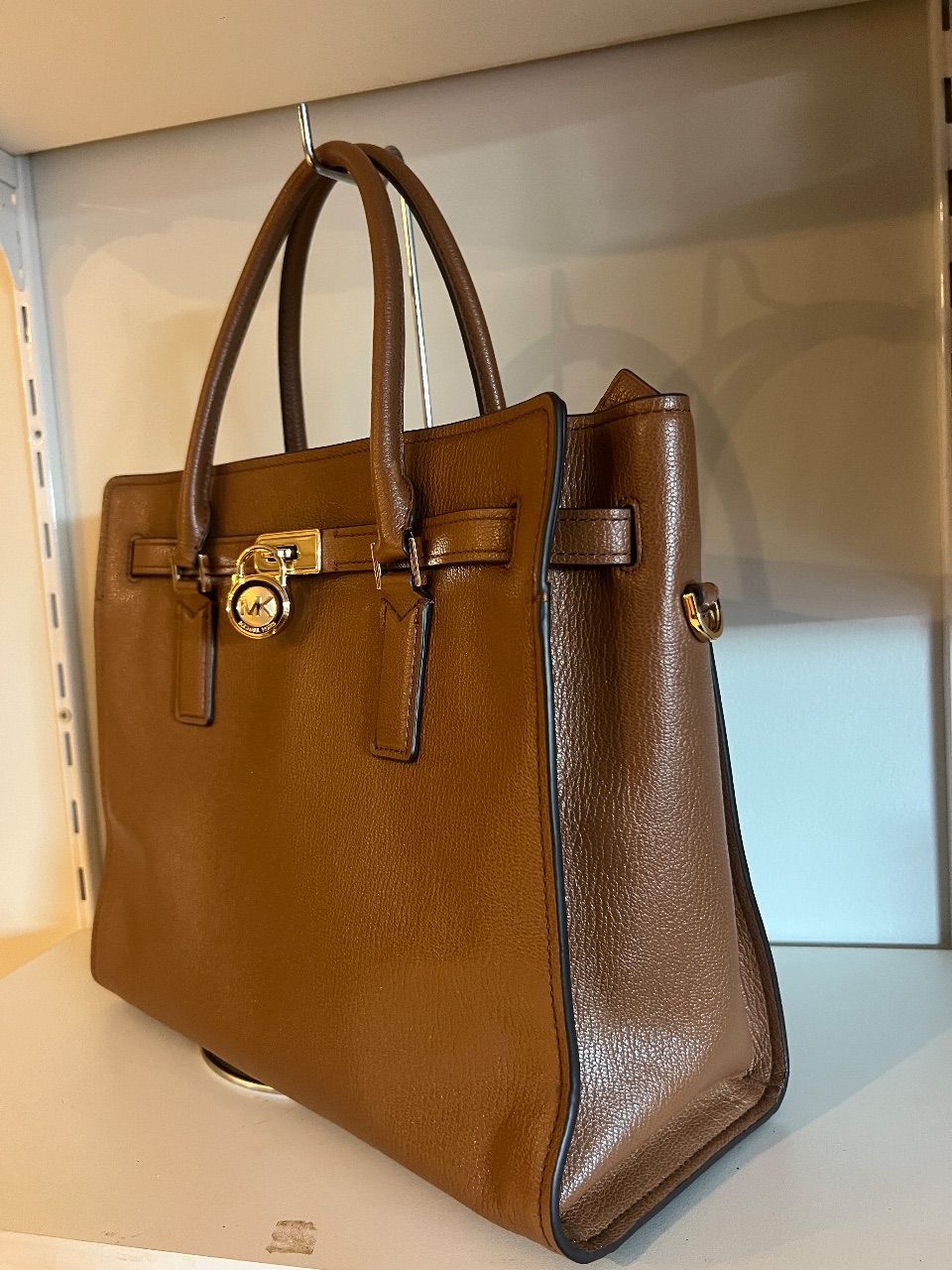 Bolsa tote de couro marrom com duas alças, cinto frontal e cadeado dourado — foto 2